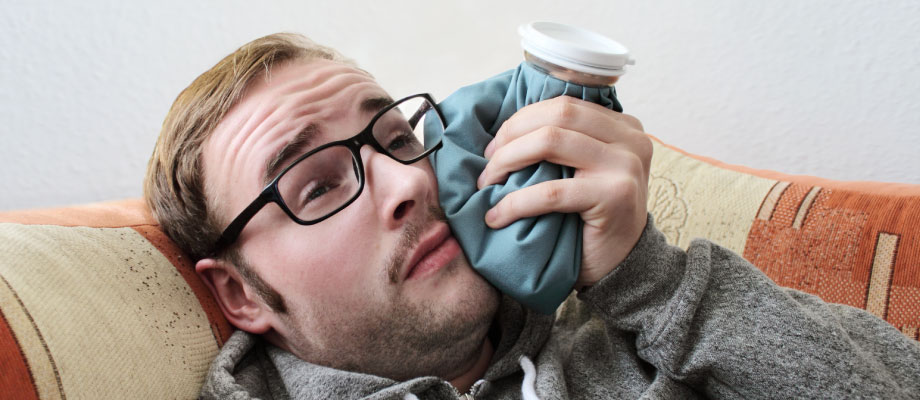 man on couch ice pack on face after root canal