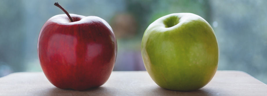 red apple and green apple sitting on wooden counter