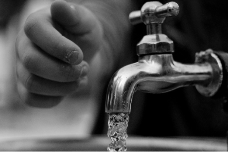 small hand reaching for a running water tap