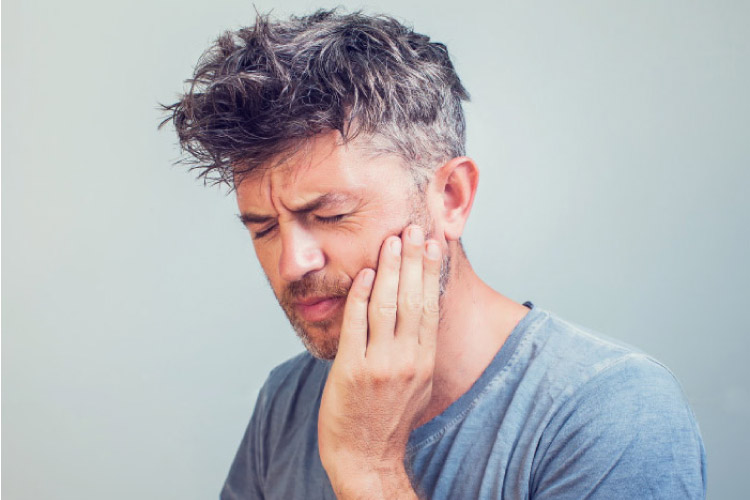 man holding his jaw and wincing with severe tooth pain