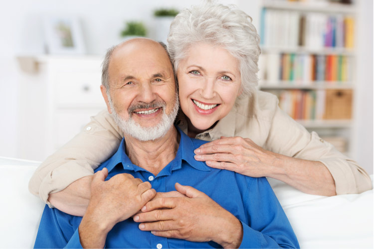 older couple hug and smile after learning about dental implants and bridges