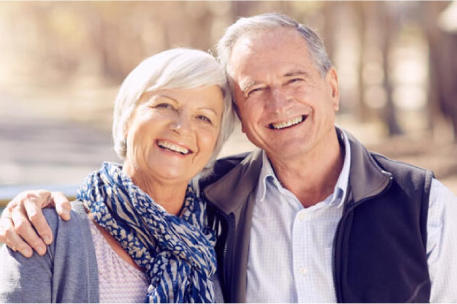 senior couple smile after receiving tooth replacements