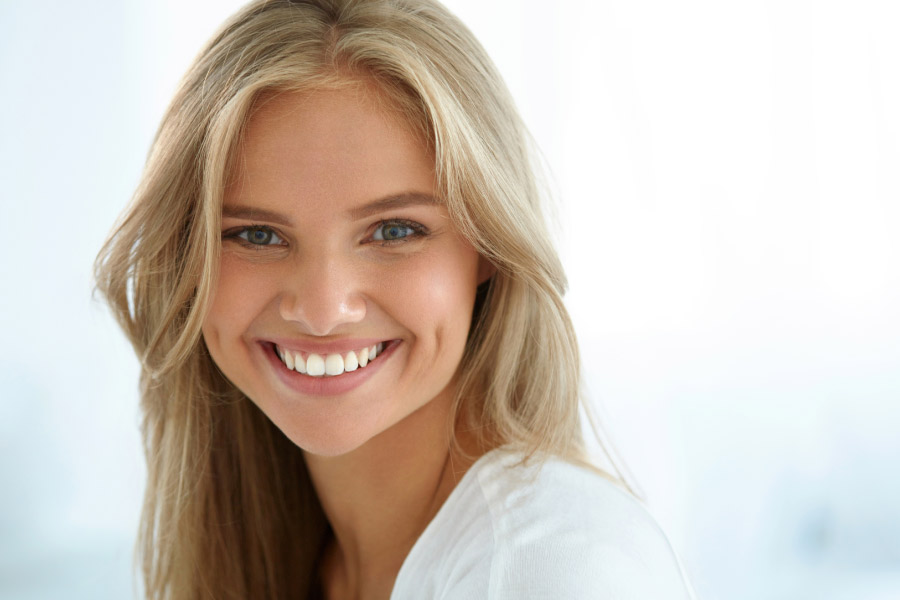 young blond woman smiles to show off her white, bright, straight teeth