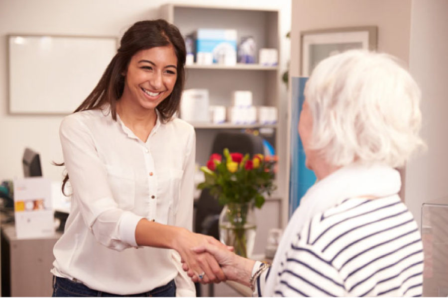 dental assistant greets a senior dental patient