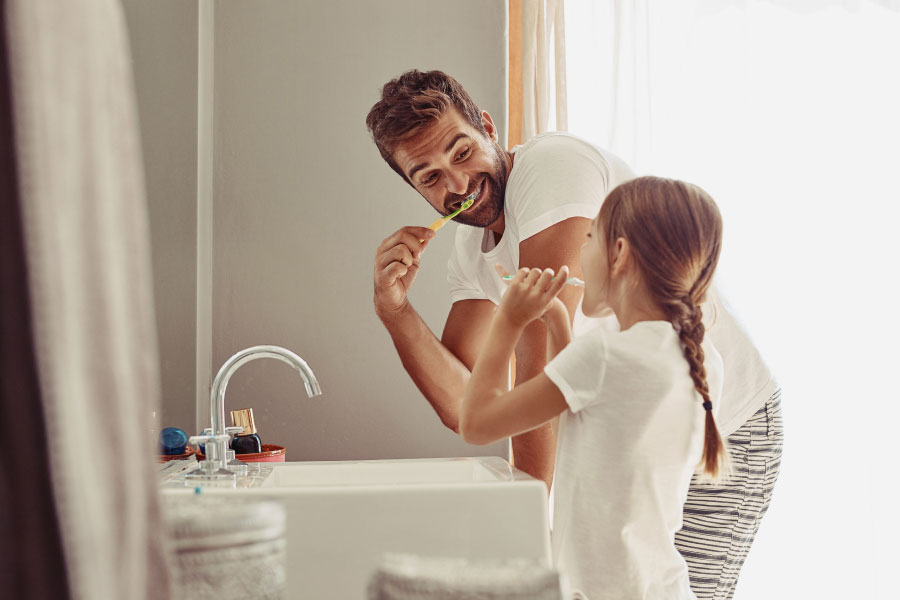 father brushes his teeth with his young daughter