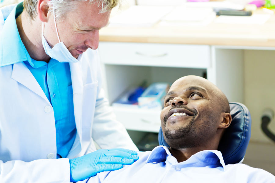 dentist consults with a man in the dentist chair about caring for his dentures