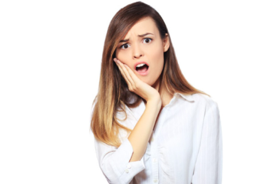 young woman holds her jaw in pain with a cracked tooth