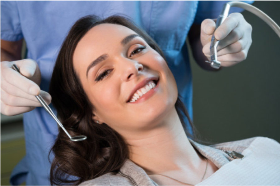 young woman smiles sitting in the dentist chair while getting a regular cleaning