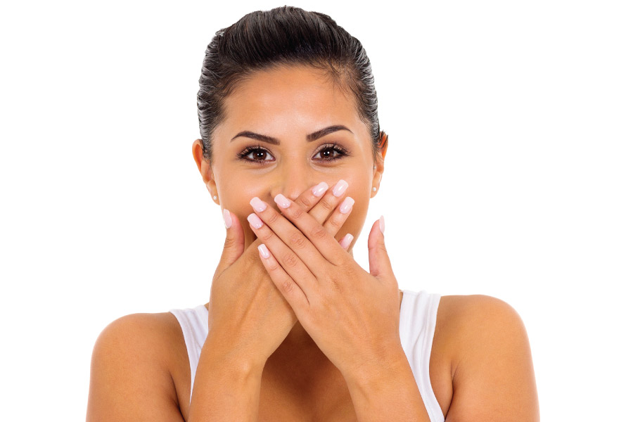 woman covers her mouth with both hands to hide bad breath